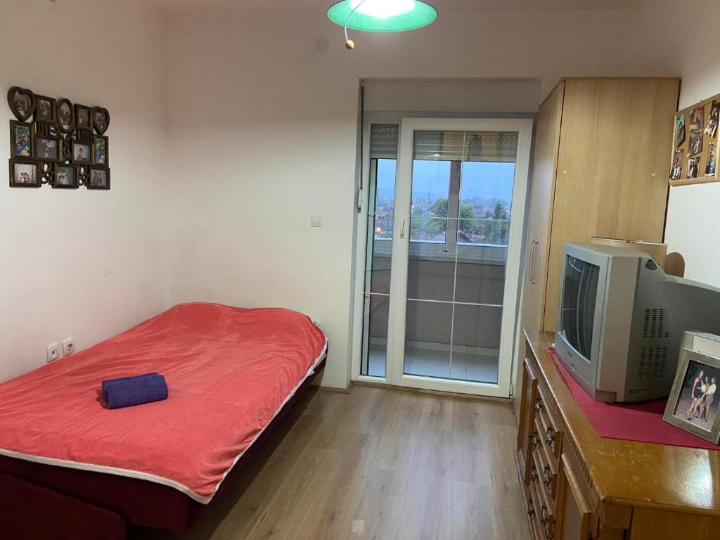 1 dormitorio con cama roja y TV en Apartman-Glavas en Smederevska Palanka