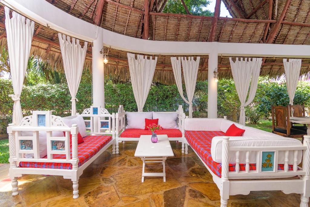 un pabellón con sillas blancas y cojines rojos en Minimi Couzy villa casaurina en Malindi