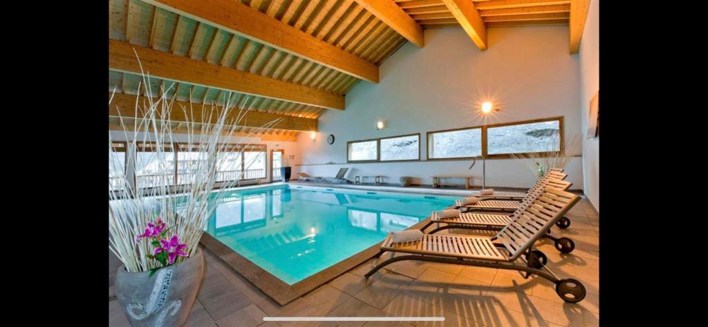 una piscina con tumbonas en una casa en Les 3 Vallées - Hameau des eaux d'Orelle - Appartement 003, en Orelle