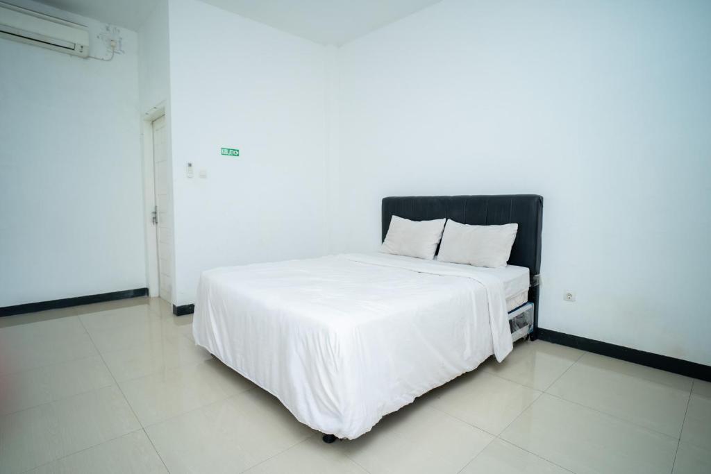 ein weißes Bett mit einem schwarzen Kopfteil in einem Zimmer in der Unterkunft KS Hotel in Cilacap