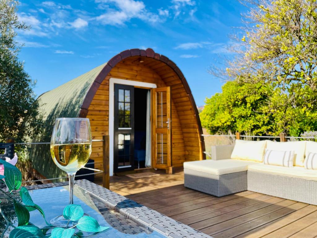 Casa cápsula con una copa de vino en la terraza en Glamping Turquesa, feel and relax in a wood house, en Corredoura