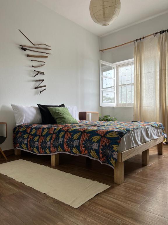 ein Schlafzimmer mit einem großen Bett mit einer bunten Decke in der Unterkunft Ponta Mina Room in São Tomé