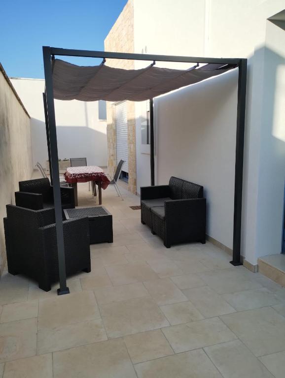 a patio with black couches and a table and awning at Onde Salentine Deluxe in Casalabate
