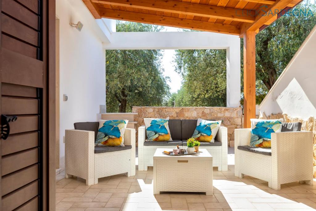um pátio com cadeiras de vime e uma mesa em ClickSardegna Casa Speranza in Villa Brionis con grande veranda em Alghero