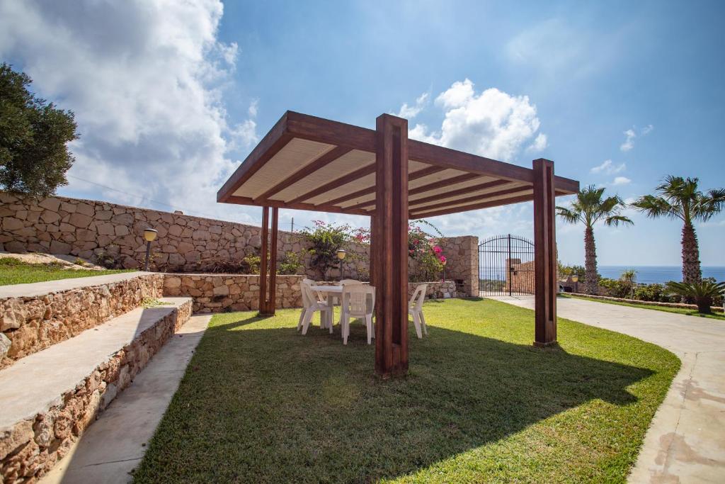 - un kiosque avec une table et des chaises sur l'herbe dans l'établissement Dammuso Ignazio, à Lampedusa