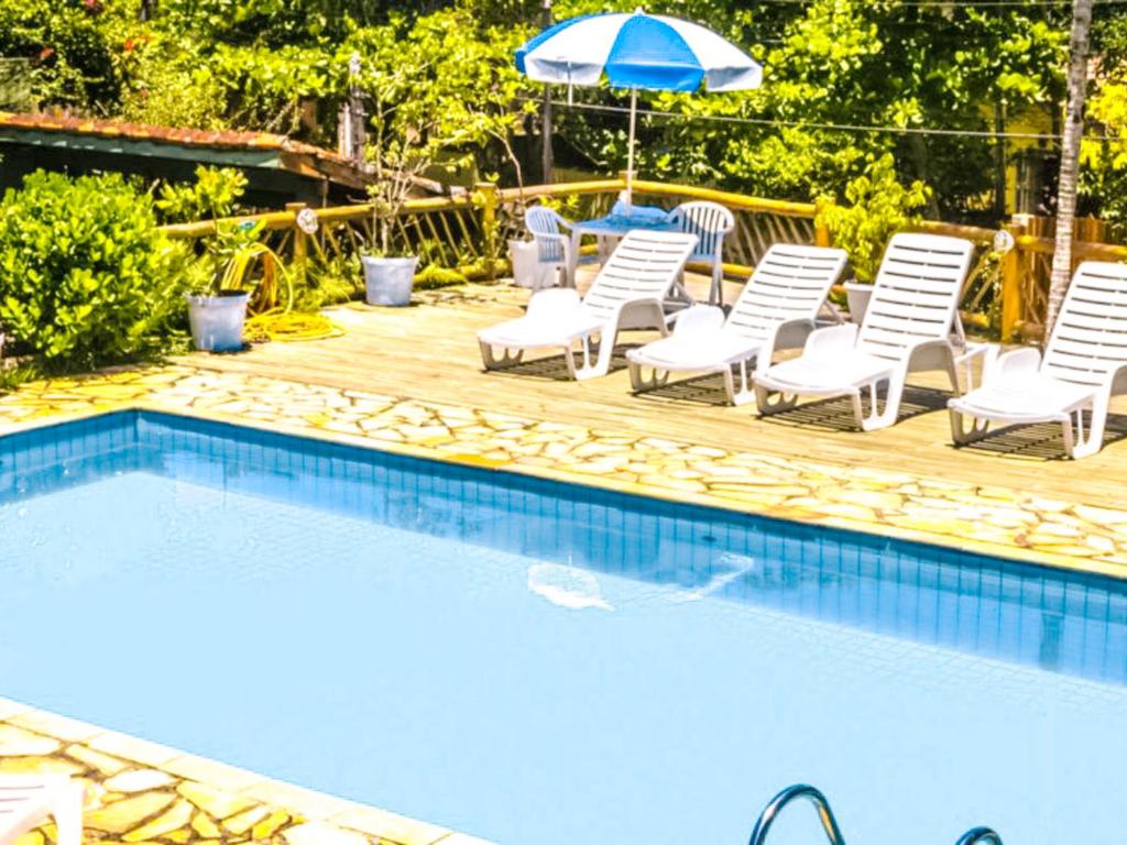 a group of chairs and an umbrella next to a swimming pool at VELINN Pousada Aporan Ilhabela in Ilhabela