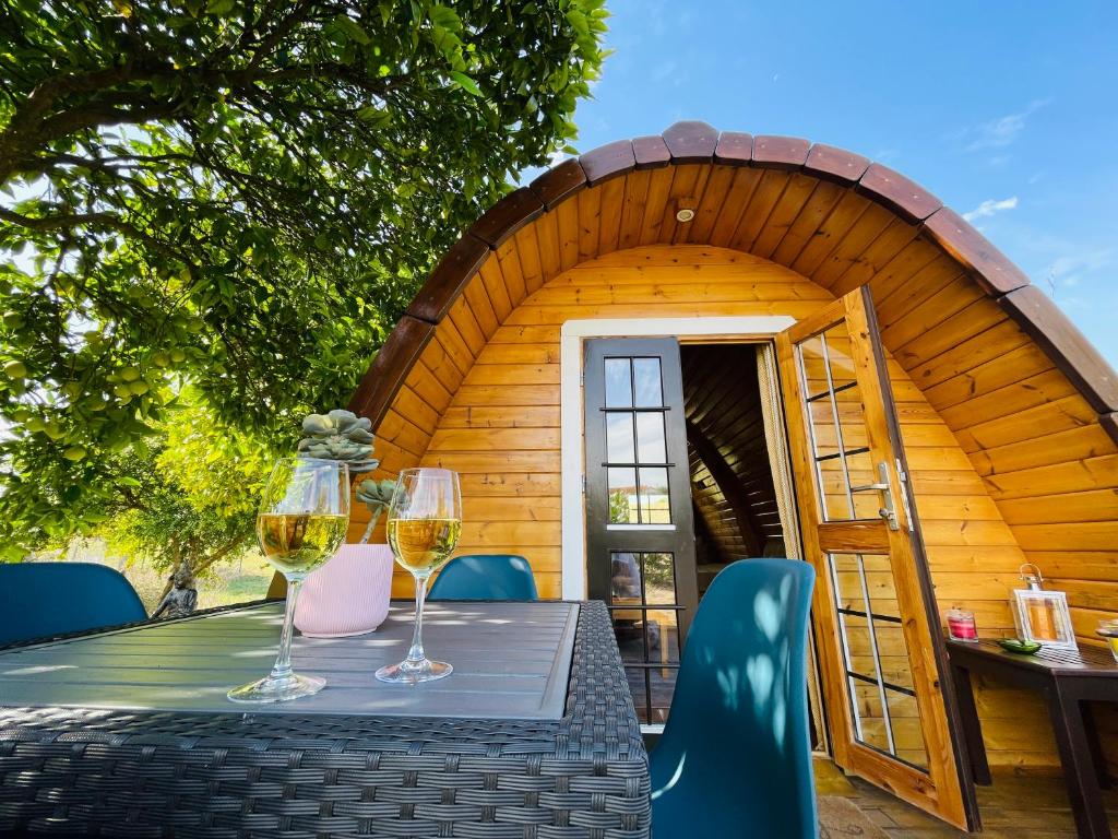 a table with two glasses of wine on top of a cabin at The Gold Pod, relax and enjoy on a Glamping house in Corredoura