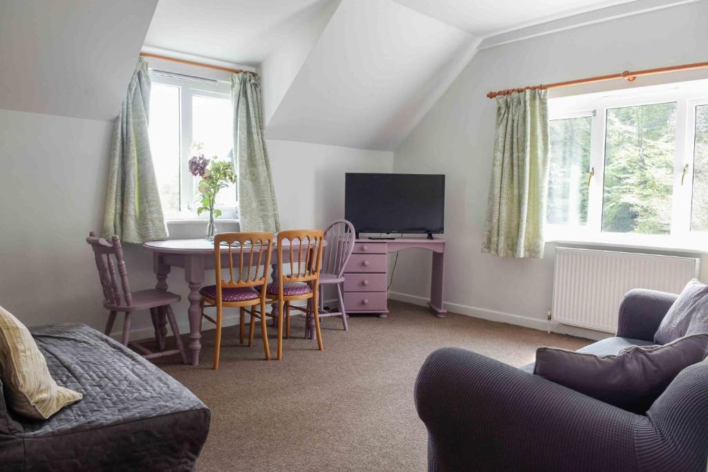 a living room with a table and a tv at Bench Tor Apartment in Plymouth