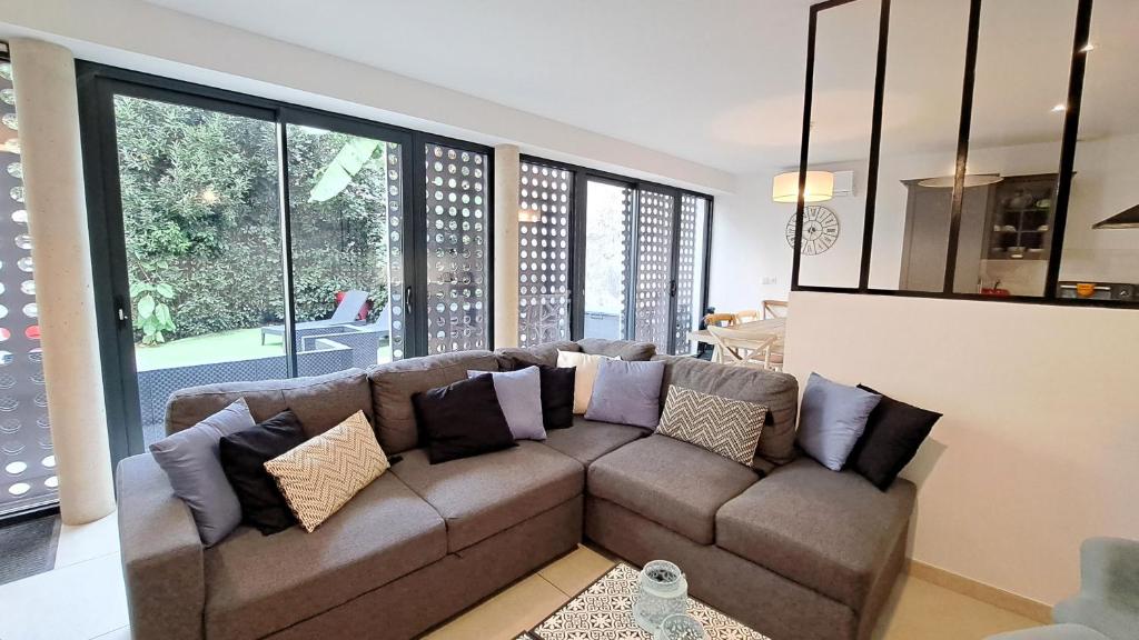 un soggiorno con divano marrone e cuscini di Maison d'architecte centre Tours jardin, climatisation, parking 5 p a Tours