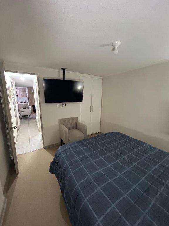 1 dormitorio con 1 cama azul y TV de pantalla plana en Cómodo Dpto en Curicó en Curicó