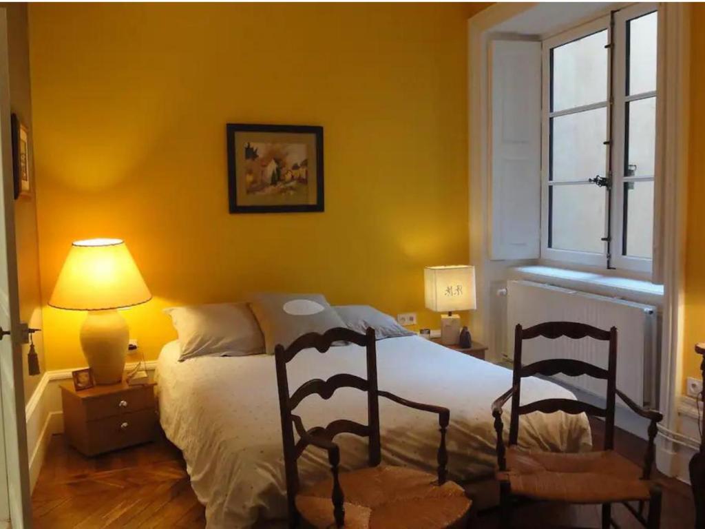 a bedroom with a bed with two chairs and a window at Les 24 colonnes in Lyon