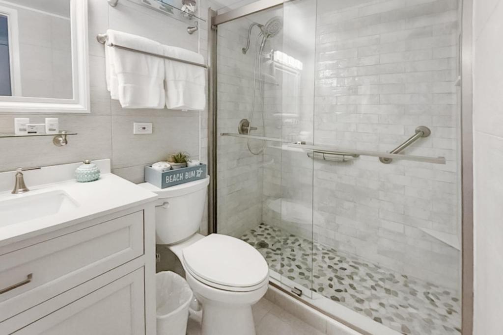 a white bathroom with a toilet and a shower at Turtle Time Suite in Satellite Beach