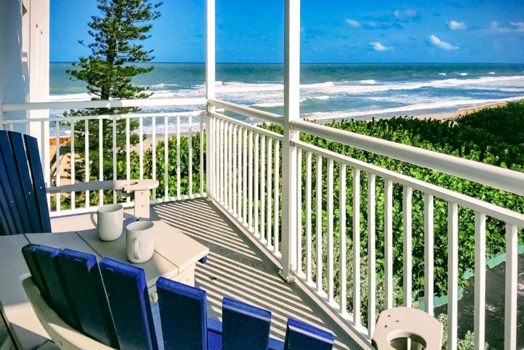 a balcony with a table and chairs and the beach at Turtle Time Suite in Satellite Beach