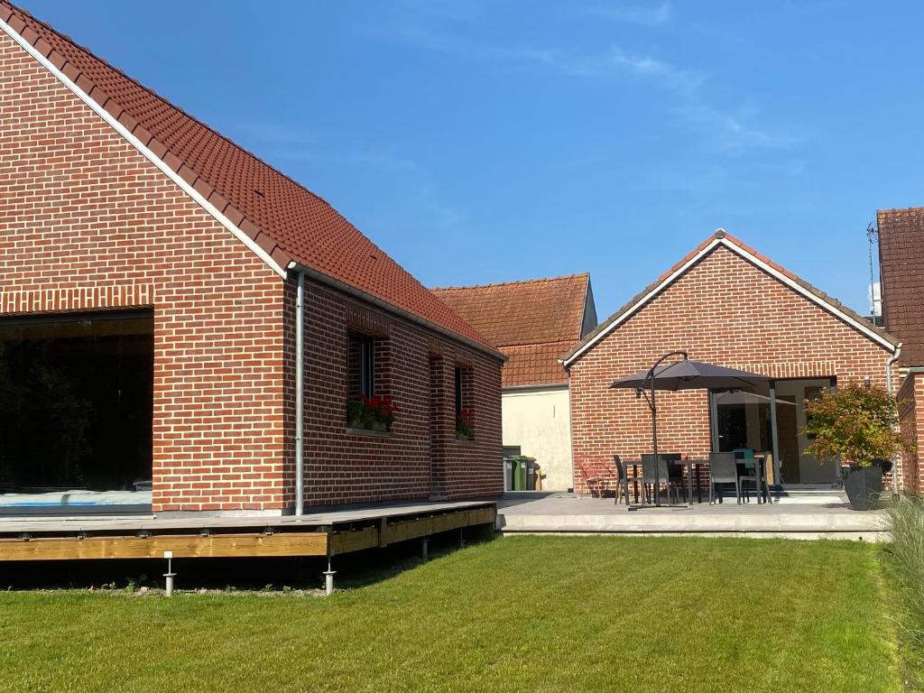 a brick building with a patio with a table and chairs at Gîte l’échappée féérique in Fresnicourt-le-Dolmen