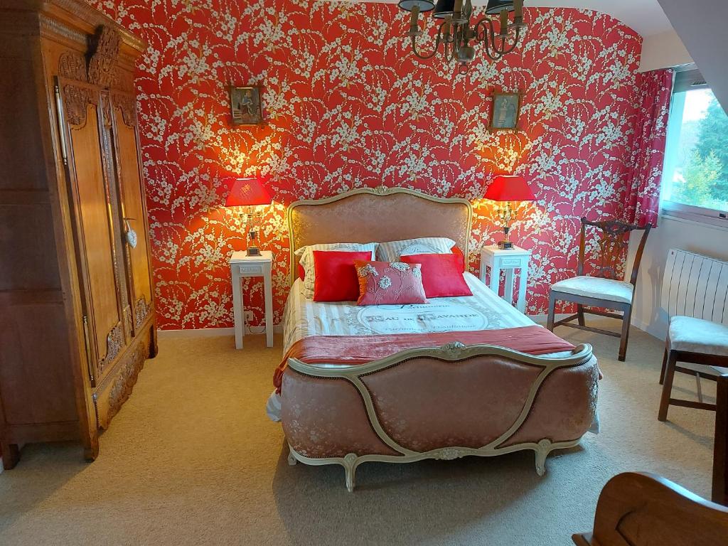 a bedroom with red walls and a bed with red pillows at Le Jardin de Wéléat in Valognes