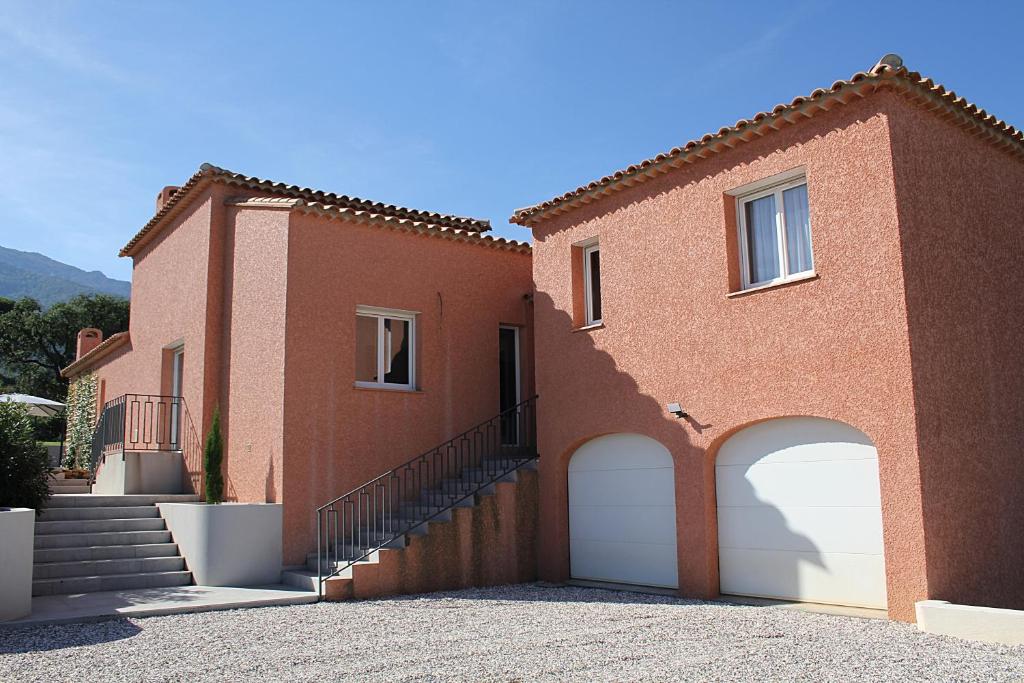 ein rotes Backsteinhaus mit zwei weißen Garagentüren in der Unterkunft Modern 4 bedroom villa, air-conditioning, swimming pool, private gardens in Laroque-des-Albères