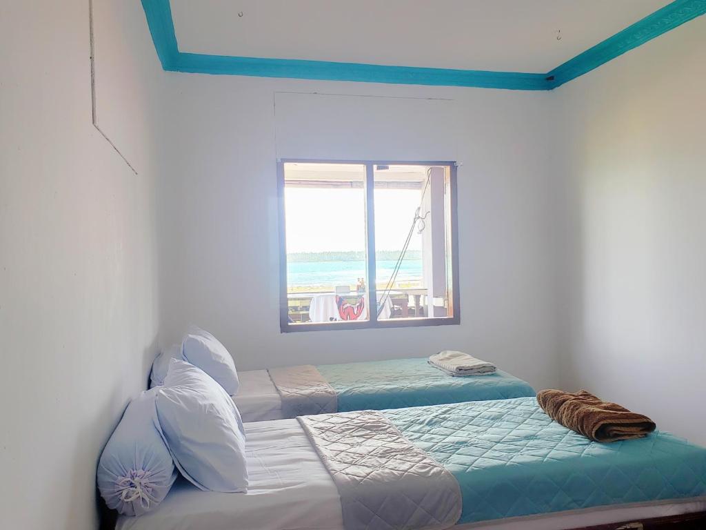 a bedroom with two twin beds and a window at Raffiel Nias in Lagudri
