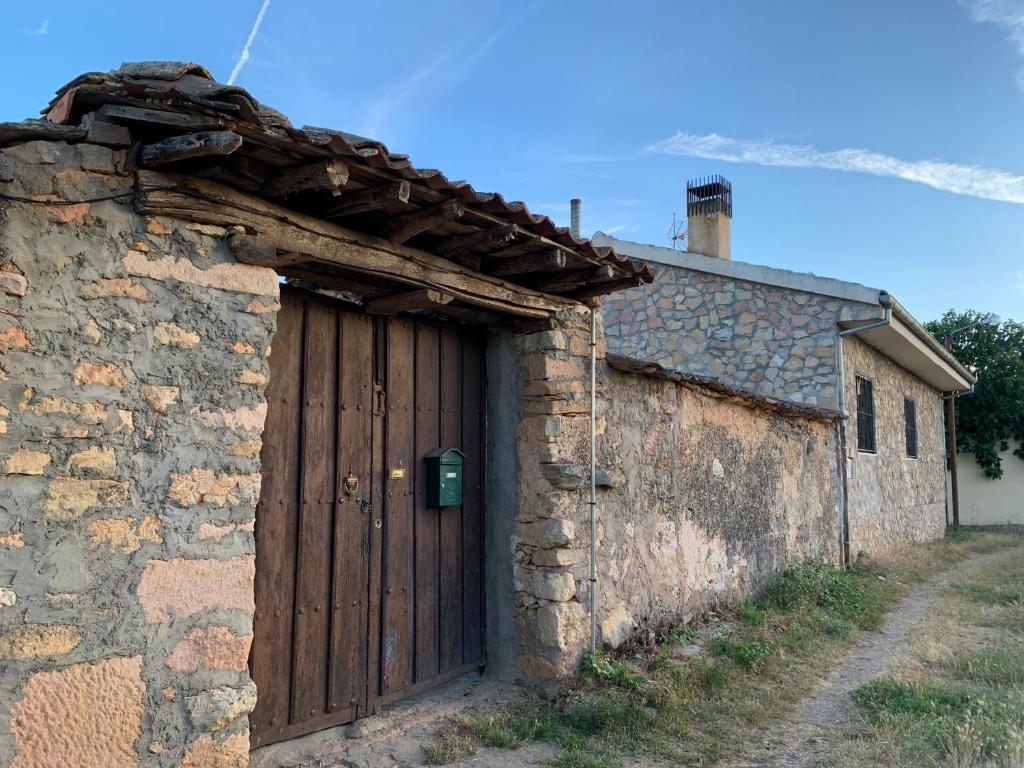 um antigo edifício de pedra com uma porta de madeira em El enebrón - Hoces del río Duratón 