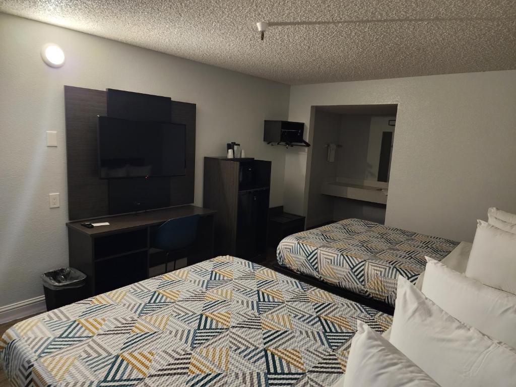 a hotel room with two beds and a flat screen tv at Motel 6 Sacramento CA Natomas in Sacramento