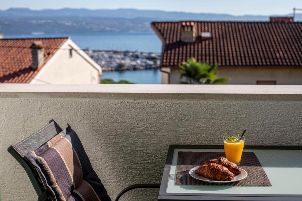a plate of food and a glass of orange juice on a balcony at Villa Beller New in Ičići