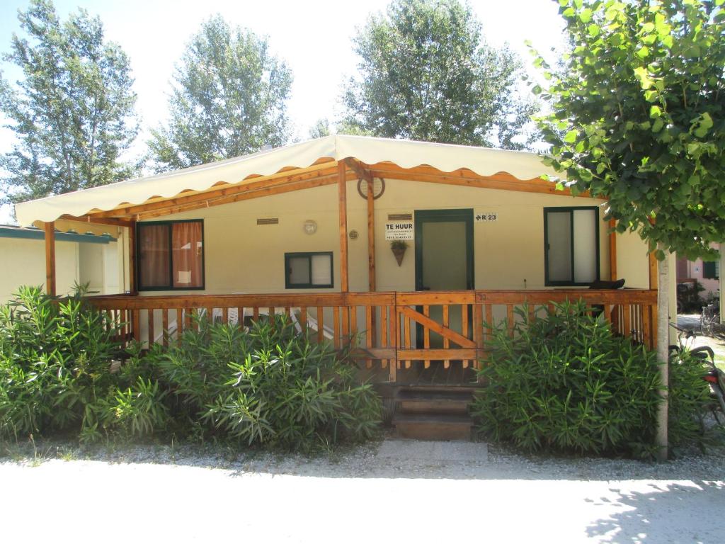 a small house with a wooden porch at Mobile home / Chalet Viareggio - Camping Paradiso Toscane in Viareggio