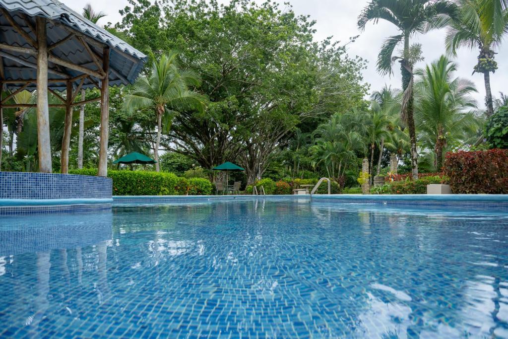 una piscina en un complejo con palmeras en Paradise Breeze 2Bdr near Quepos Manuel Antonio, en Quepos