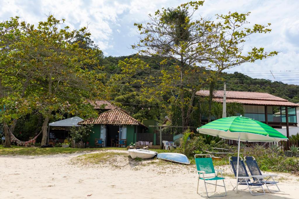 a couple of chairs and an umbrella on a beach at Pé na areia, tranquilidade,conforto,2 quartos, ar-cond, Wi-Fi, pet-friendly, 7 pessoas, in Bombinhas