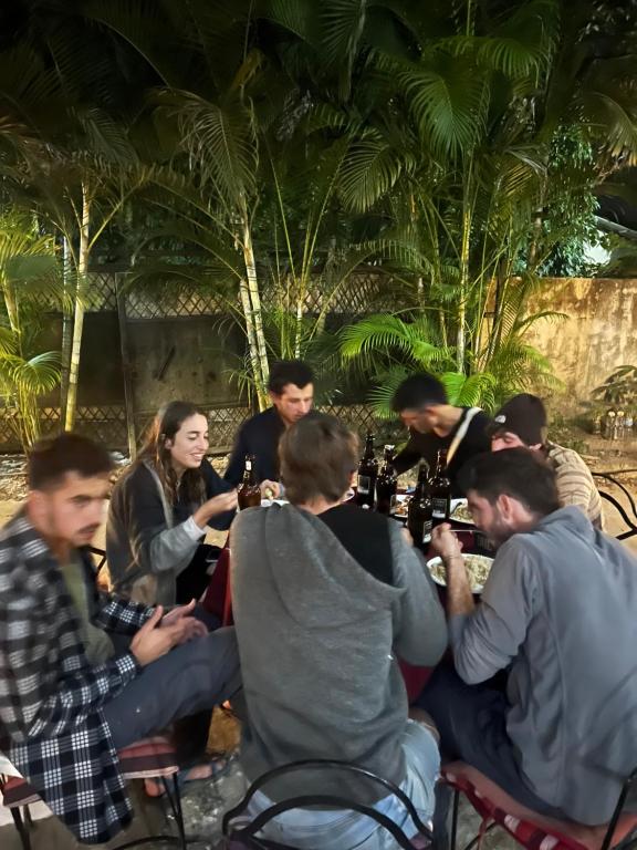 eine Gruppe von Menschen, die mit Weinflaschen um einen Tisch sitzen in der Unterkunft Sauraha BnB in Sauraha