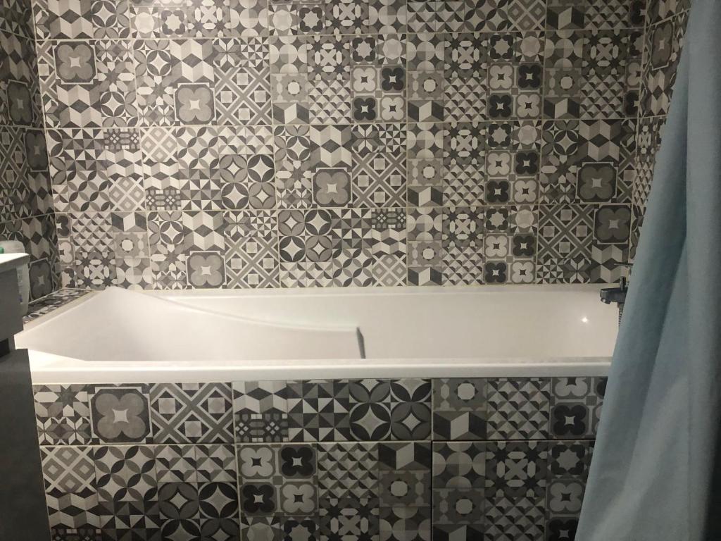 a bath tub in a bathroom with a tile wall at Jolie chambre à Nanterre Préfecture proche La Défense Aréna Campus SNCF et Paris in Nanterre