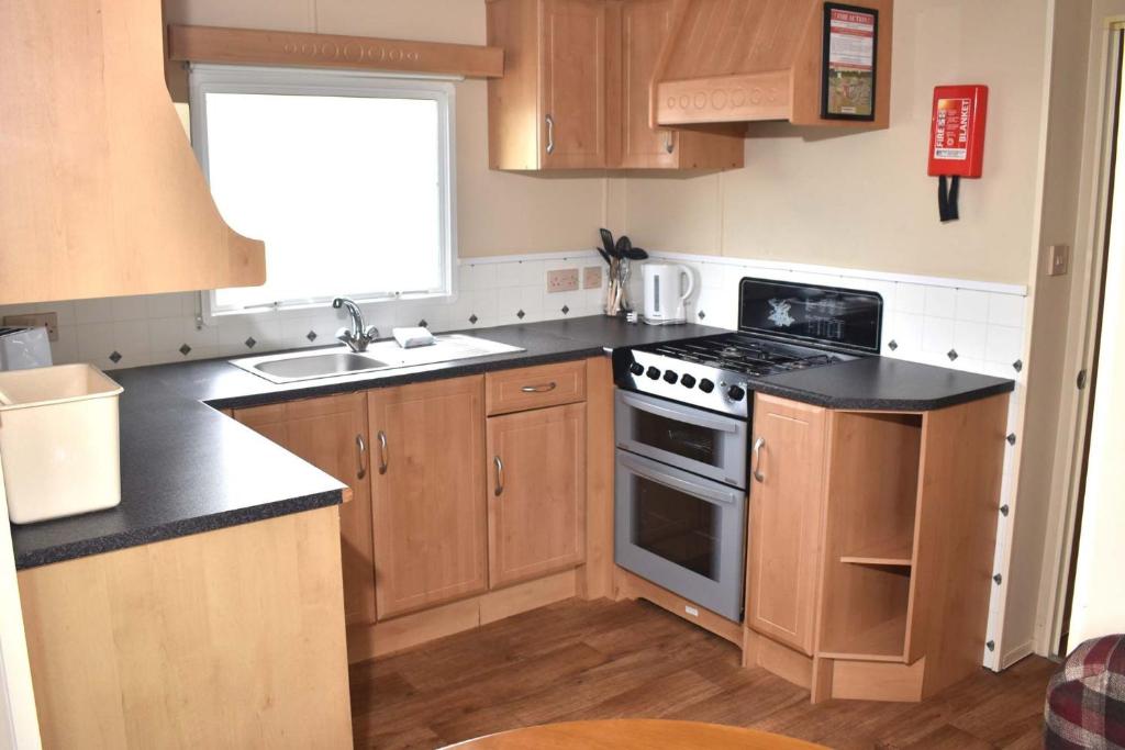 a kitchen with wooden cabinets and a stove top oven at Albany Bronze - pet friendly LC10 in Minehead