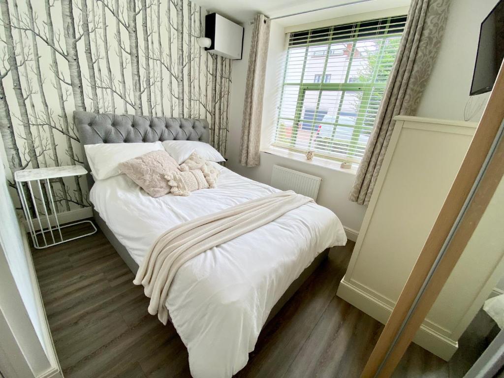 1 dormitorio con 1 cama con sábanas blancas y ventana en Cosy 1 bed “pied-a-terre”, en Northampton