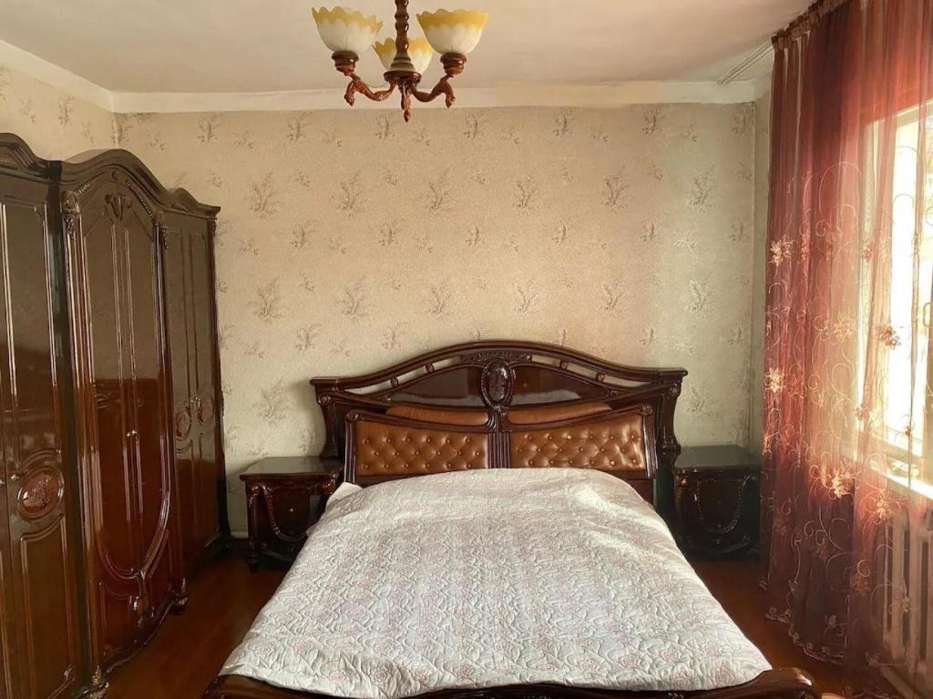 a bedroom with a wooden bed and a chandelier at Room in the house, with mountain views and squirrels in the yard in Almaty