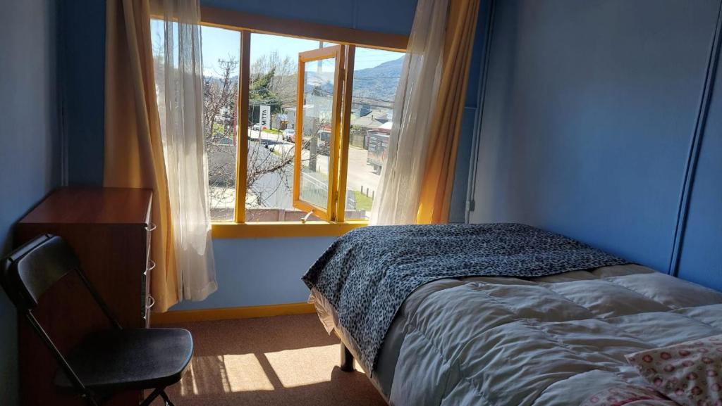 a bedroom with a bed and a window and a chair at Pies a tierra in Coihaique