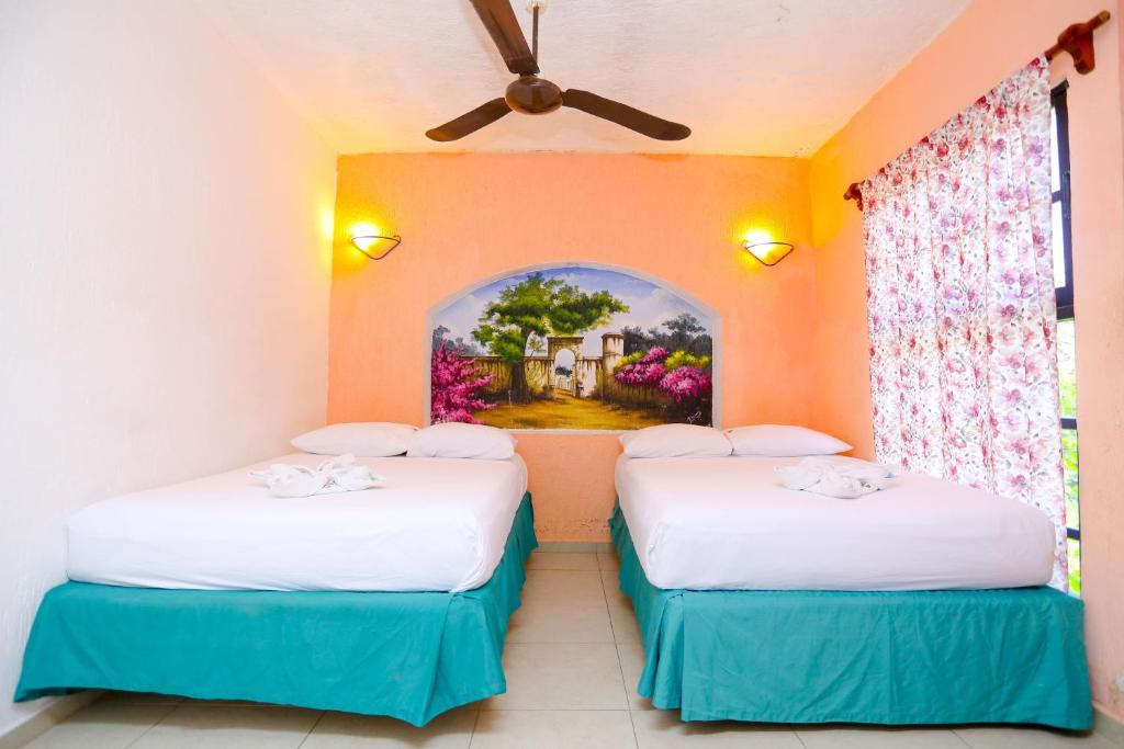 two beds in a room with a painting on the wall at Hotel Hacienda Cancun in Cancún