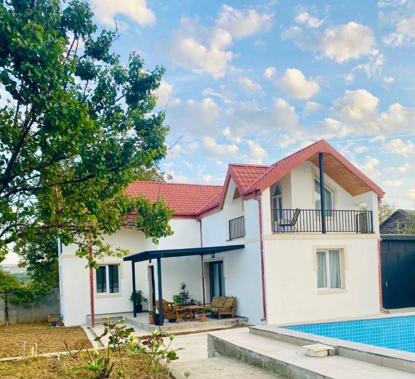 ein weißes Haus mit einem roten Dach und einem Pool in der Unterkunft Vila Mtatsminda in Okrokana