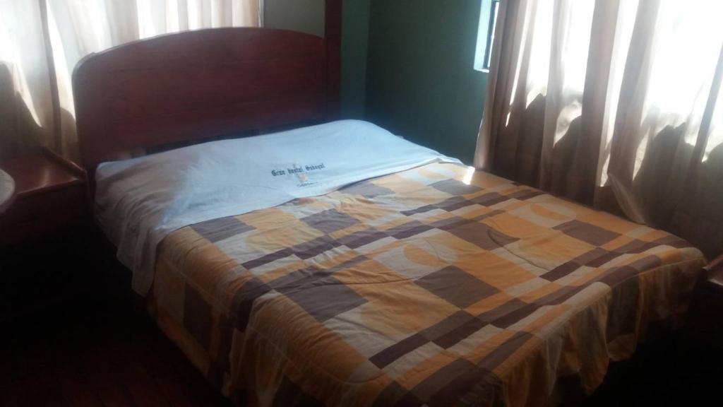 Una cama con una manta a cuadros en un dormitorio en Rosario Melchora Vásquez Rodriguez, en Cajamarca