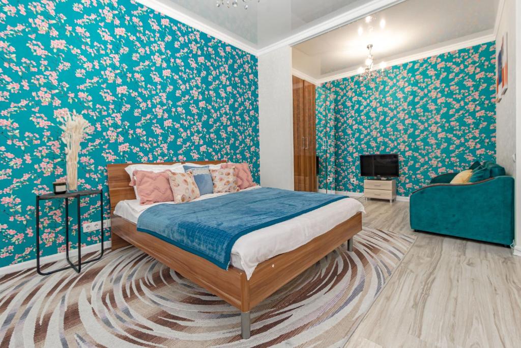 a bedroom with a bed with blue and white floral wallpaper at Expo Promenade Уютная квартира возле Expo in Prigorodnyy