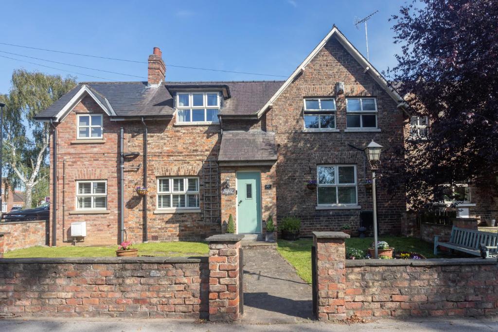 a brick house with a brick fence in front of it at Pinfold Cottage York in York