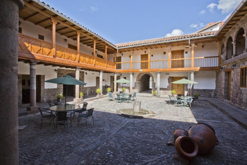 un patio al aire libre con mesas, sillas y sombrillas en Tierra Viva Cusco Centro en Cusco