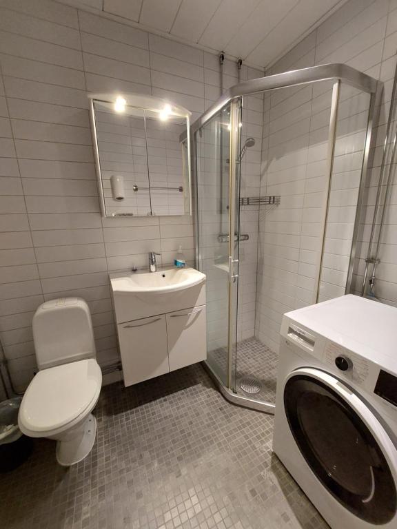 a bathroom with a shower toilet and a washing machine at Home Inn LNG20 in Stockholm
