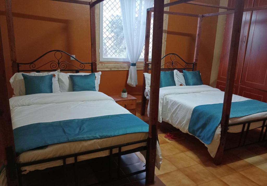 two beds in a room with blue and white at KIJIJI VILLAGE in Emali