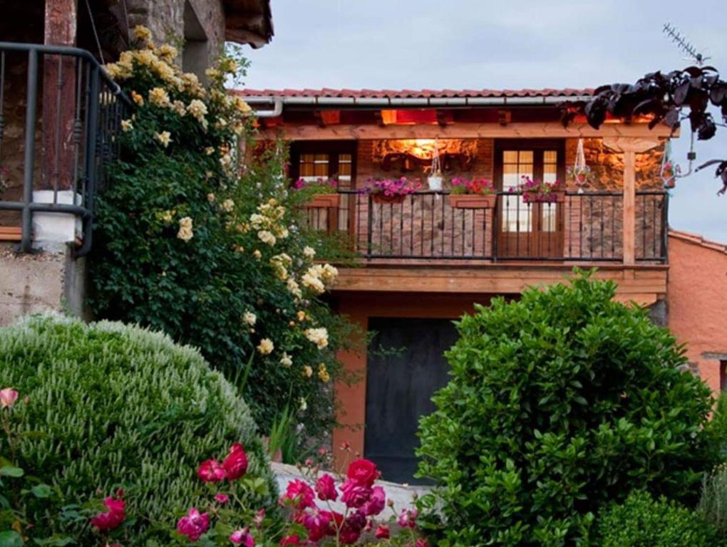 a building with a balcony with flowers on it at El Rincón de la Rosa in Brugos de Fenar