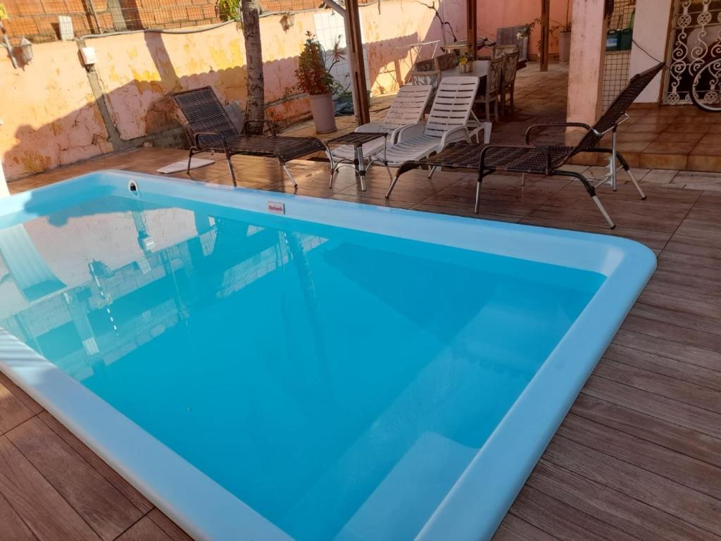 a blue swimming pool with chairs and a table at Aconchego in Guarujá
