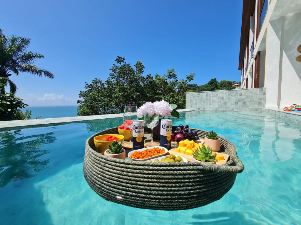 CairuにあるApartamento em Morro de São Paulo (BA)のプールサイドのテーブルに食べ物と飲み物のトレイ