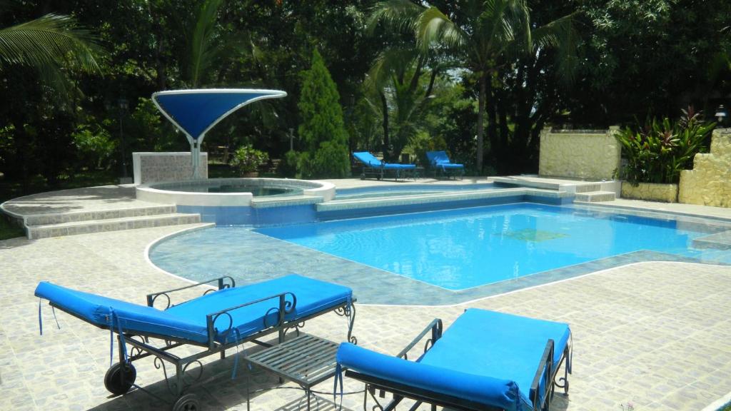 una piscina con sillas azules y una fuente en Casa Campestre El Peñon 5 Habitaciones, en Girardot