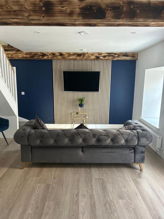 sala de estar con sofá y pared azul en A Village Gem, en Mullingar