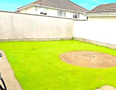a yard with green grass and a white wall at Mountain lodge in Dundalk
