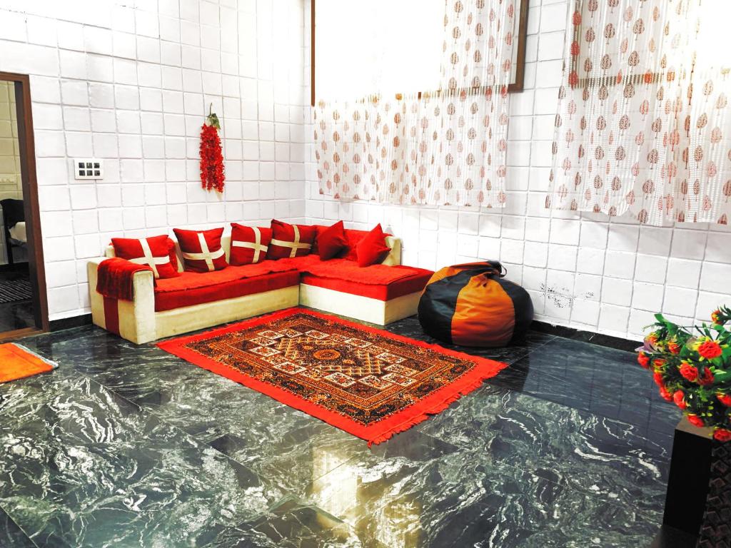 sala de estar con sofá rojo y suelo de mármol en Mannat Inn TS Mysore - Premium Homestay en Mysore