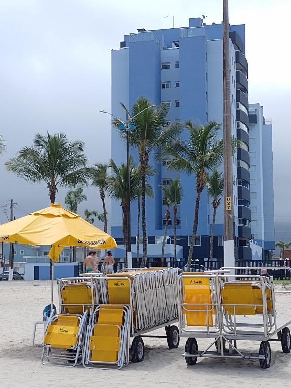 a group of chairs and an umbrella on a beach at Espaço Sol, Mar & Cia in Bertioga