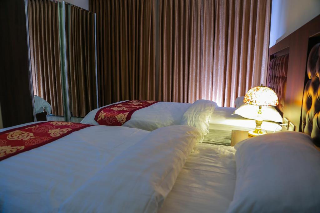 a hotel room with two beds and a lamp at Qaser Al-Sultan Hotel Suites in Amman